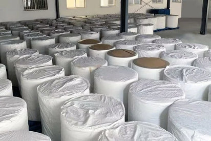 Multiple rolls of white fabric stacked in a warehouse setting